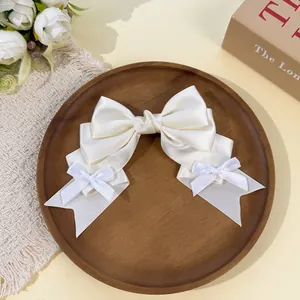 Close-up of a white satin Lolita-style bow hair clip with dainty ribbon accents