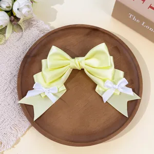Detail view of pale yellow Lolita style satin bow hair clip on wooden plate