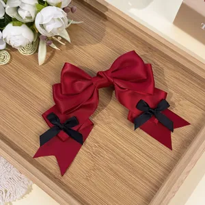 Detail of a sweet red satin bow hair clip with black mini bows in Lolita style.