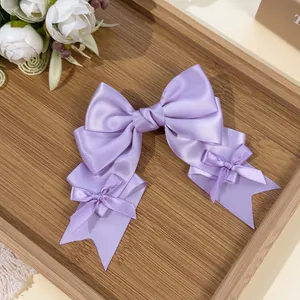 Close-up of elegant purple satin Lolita style bow hair clip with ribbons on wooden tray