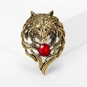 Close-up of vintage wolf head brooch with red gemstone in antique gold finish