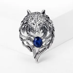 Macro view showing details of a vintage silver wolf head brooch with an oval blue gemstone