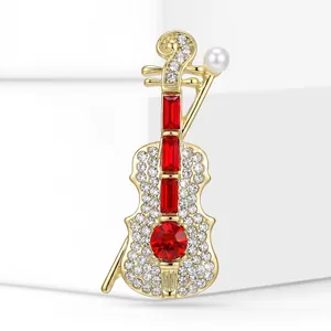 Primo piano di elegante spilla a violino dorata con pietre rosse e cristalli