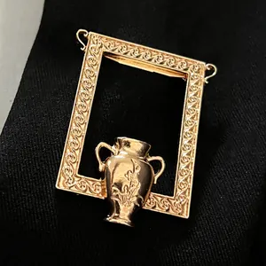 Nahaufnahme der eleganten goldenen Bilderrahmen-Brosche mit kleiner Vase im Detail