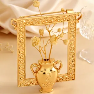 Nahaufnahme einer eleganten Goldrahmen-Vasen-Brosche mit getrocknetem Blumenstrauß-Detail