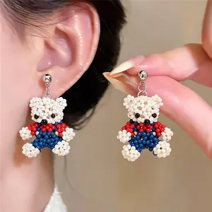 Detail view of cute handmade beaded bear earrings with red and blue clothing accents