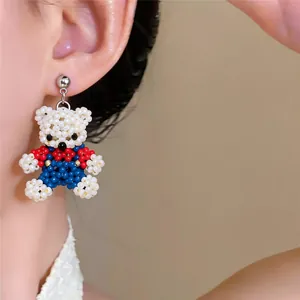 Detail shot of a handmade beaded bear earring worn on ear, featuring white, red and blue beads
