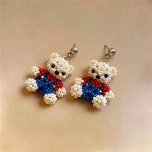 Macro detailed view of handmade beaded bear earrings featuring red, blue and white beads