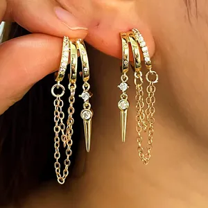 Close-up detail of stylish gold hoop earrings with zircon fringe and spike charms for women