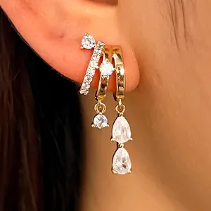 Close-up detail of gold-tone layered ear cuffs with sparkling zircon fringe charms