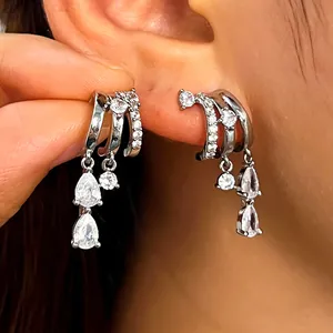Close-up of silver-plated irregular hoop earrings with dangling pear-cut zircons.