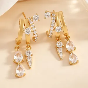 Macro detail of elegant gold triple-hoop earrings with zircon teardrop dangles