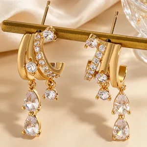 Close-up of irregular gold-tone hoop earrings with zircon tassels and water-drop stones.