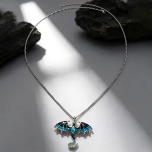 Detailed shot of a Gothic dragon pendant necklace with blue wings on a dark stone background