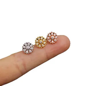 Three flower-shaped stainless steel screw stud earrings with cubic zirconia on a finger.
