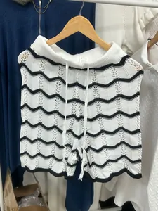 Détail d'un short en maille avec des motifs ondulés noirs et blancs et une maille ajourée.