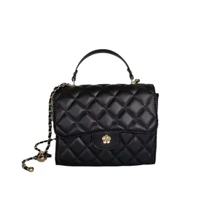 Detailed front view of a black quilted mini handbag with gold flower clasp and chain strap
