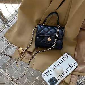 Close-up detail of a black quilted mini handbag with a gold chain strap on a blazer