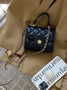 Detailed view of black mini quilted handbag with gold flower clasp and chain strap