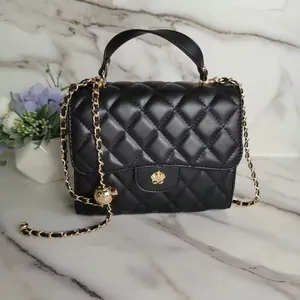 Close-up of black quilted mini handbag with gold flower clasp and chain strap detail.