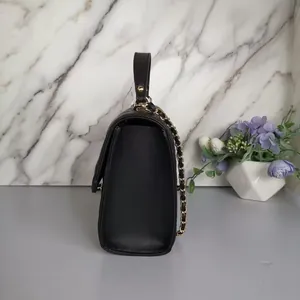 Side view of a black mini diamond quilted chain handbag with elegant gold hardware