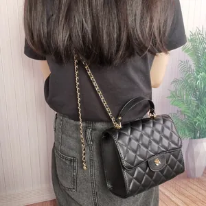 Back view of a black quilted handbag with elegant gold chain strap on a model