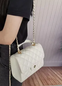 Elegant detail of a white quilted mini square bag featuring a gold leather-intertwined chain strap