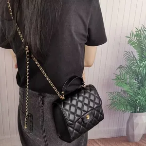 Close-up of a black quilted leather chain bag with gold accents worn by a model
