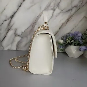 Side view of a white quilted mini bag with a luxury gold chain strap detail