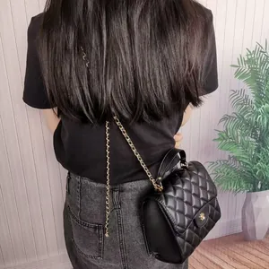 Back view of elegant black quilted mini crossbody bag with gold chain strap on model