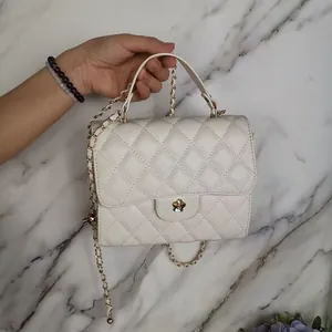 Detailed view of a stylish white quilted mini handbag with a gold chain strap and clasp.