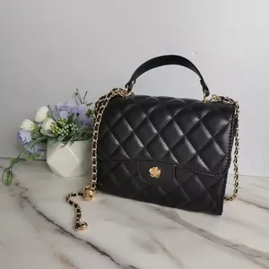 Close-up of black quilted leather handbag with elegant gold flower clasp