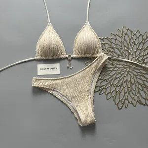 Close-up of cream textured triangle bikini set with gold star and pearl charm detail