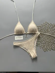 Close-up detail of cream textured bikini set with decorative metal ring and tassel