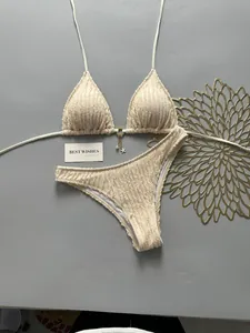 Detailed flat lay of cream textured bikini set featuring a gold starfish pearl charm