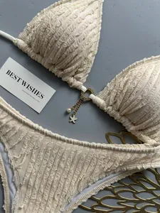 Detail view of cream textured bikini set featuring a starfish charm and pearl accents