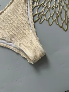 Macro view of cream ruffled texture fabric detail on minimalist bikini bottom swimwear