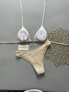 Detailed view of cream textured bikini set with ruffled fabric and golden star charm accessory.