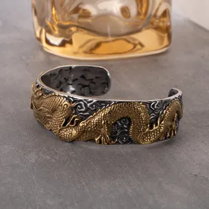 Detail view of vintage dragon cuff bracelet with intricate gold relief and silver clouds.