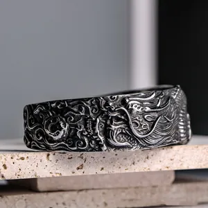 Close-up detail of a vintage titanium steel cuff bracelet featuring intricate dragon engraving