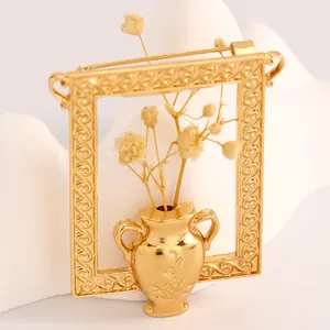 Macro view of a creative gold picture frame brooch with a miniature vase detail.