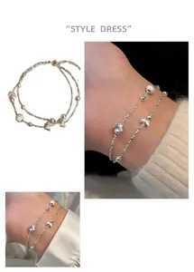 Gros plan d'un bracelet en argent double couche avec breloques papillon et perles