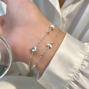 Vue détaillée d'un bracelet double couche en argent avec papillon et perles polies.