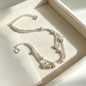 Élégant bracelet double couche en argent avec papillon et perles dans un plateau à bijoux