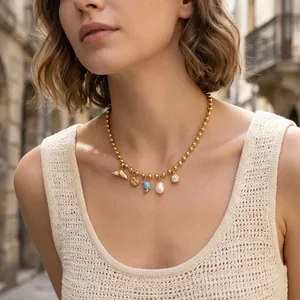 Primo piano di una collana esotica a sfere dorate con ciondoli di perle e zirconi.