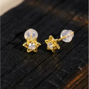 Vue macro détaillée d'élégantes boucles d'oreilles étoile à six branches dorées avec zircon