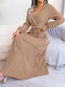 Detail of elegant taupe pleated maxi dress featuring a cross V-neck and tie waist.