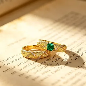 Bague vintage tressée en or avec émeraude de culture posée sur une page de livre ancien.