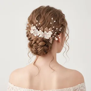 Eleganter Braut-Haarkamm mit goldenen Blättern und weißen Blüten auf Hochsteckfrisur.