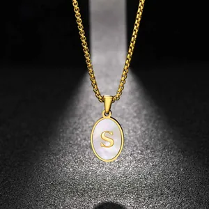 Detailed view of a gold stainless steel oval pendant necklace with white shell and letter S